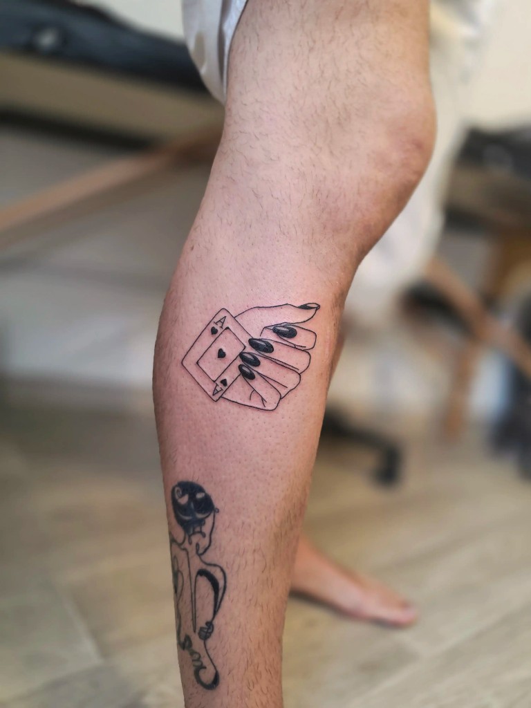 Tatouage main tenant un as de pique sur le mollet