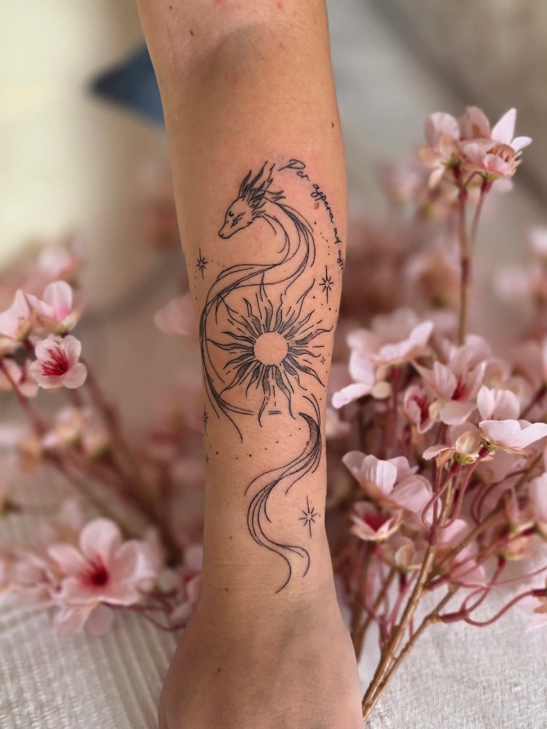 Tatouage dragon et soleil fine line sur l'avant-bras