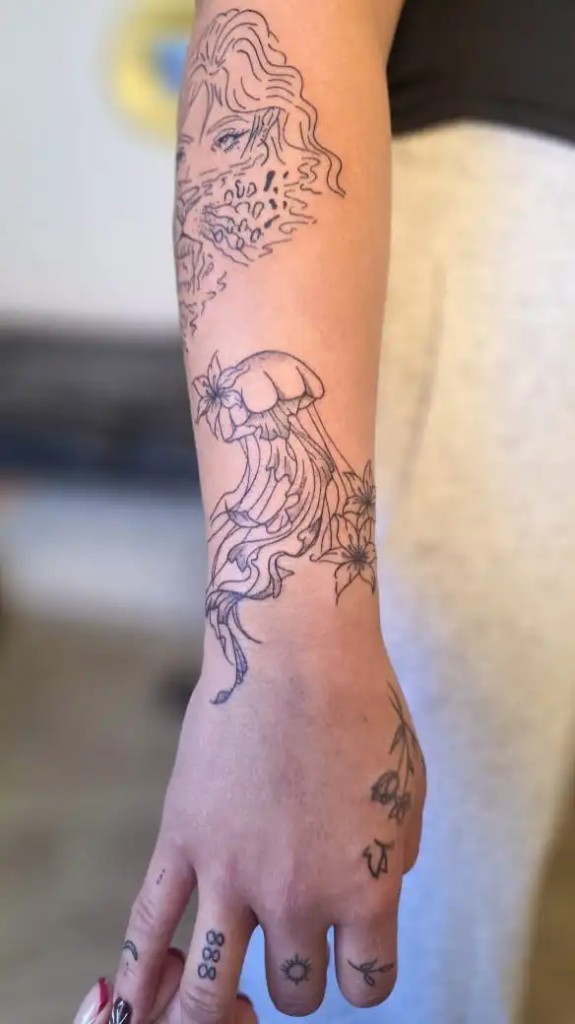 Tatouage méduse et fleurs fine line sur l'avant-bras