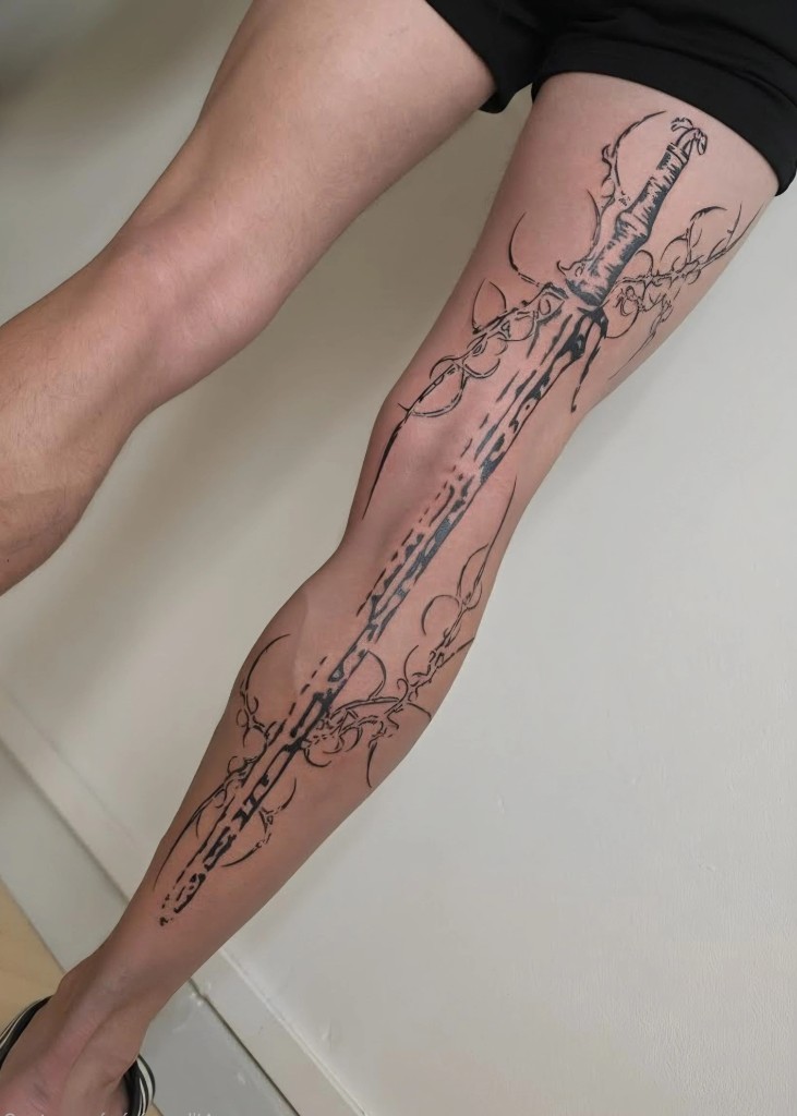 Tatouage épée blackwork sur la jambe